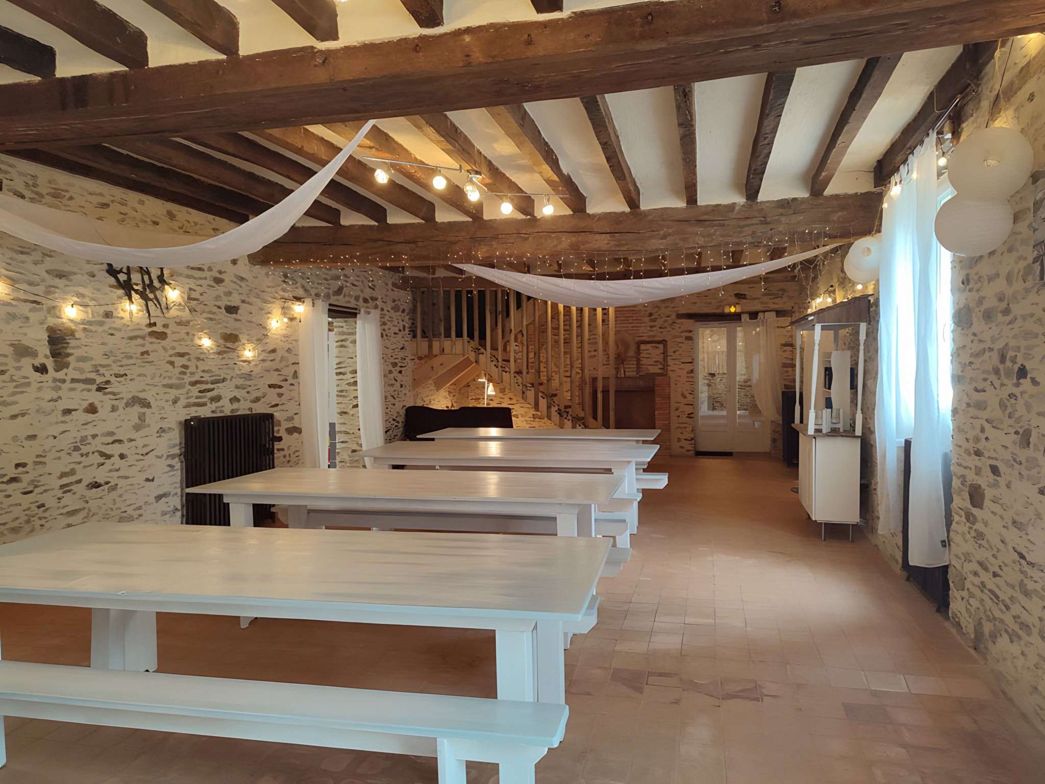 La Bâtisse : murs de pierre, poutres, grandes tables et guirlandes